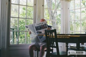 Old man reading a newspaper in his own home