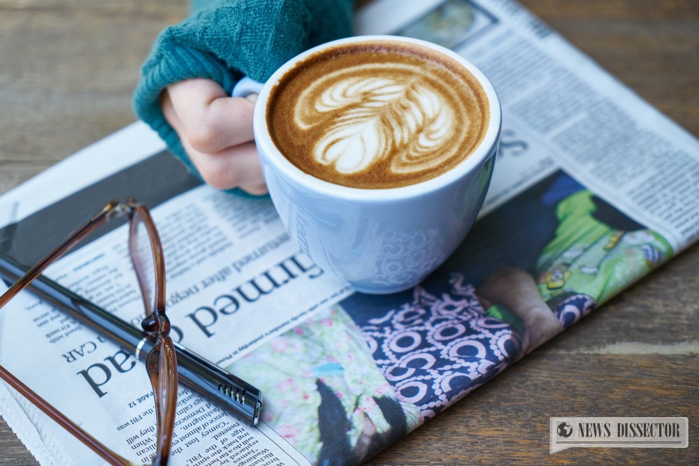 A woman having a relaxing time, reading the paper, drinking some coffee