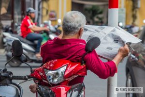 Man reading a newspaper on a scooter